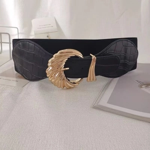 Detail of wide black elastic waist belt with gold crescent buckle and croc-texture