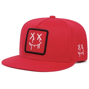 Dettaglio cappello snapback rosso con ricamo smiley e trama in tessuto di cotone twill