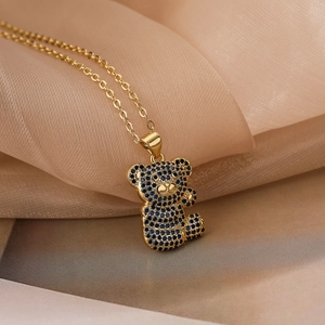 Gold plated bear pendant necklace with blue and black zircon on silk fabric background
