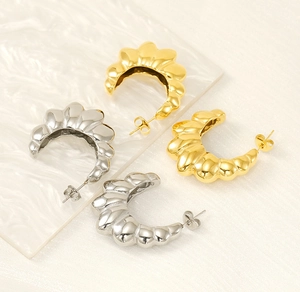 Detailed view of C-shaped hoop earrings with shell texture in gold and silver finish