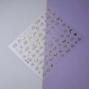 Detailed macro view of gold embossed moon and star nail art decals on a purple background