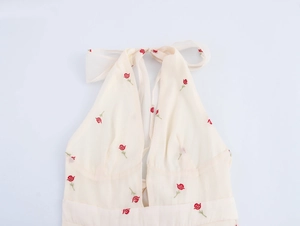 Detail of floral rose embroidery on a beige halter neck dress with backless lace-up ties