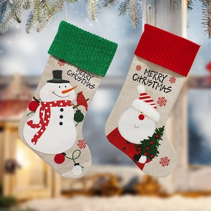 Linen Christmas stockings with Santa and Snowman patterns hanging on pine branches