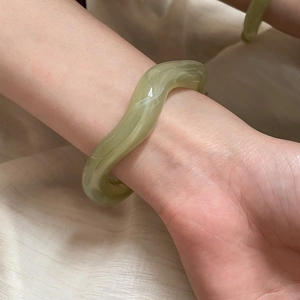 Close-up of wavy irregular green acetate bangle with marble texture on wrist