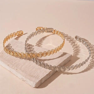 Gold and silver twisted hollow metal choker necklaces on stone texture display