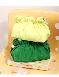 Dettaglio di borse cosmetiche arricciate in giallo e verde con cerniera a perla lucida