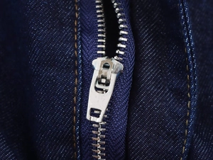 Makroaufnahme von robustem Metallreißverschluss und Nähten auf dunkler Denim-Jacke