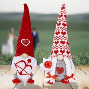 Detail of couple Valentine Gnomes holding rose and heart bow on wooden floor