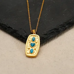 Gold plated stainless steel necklace with turquoise heart pendant on a stone background