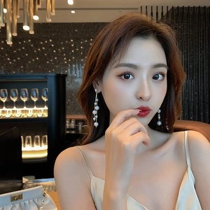Elegant long pearl tassel earrings with gold chain and zircon studs on a model
