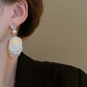 Close-up of elegant shell tassel earrings with zircon studs worn by a female model