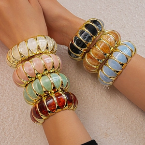 Detail of stacked acrylic resin bracelets with gold metal spacers in various colors