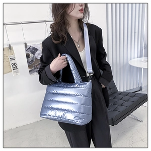 Metallic blue quilted padded tote bag with adjustable strap worn by model in black blazer