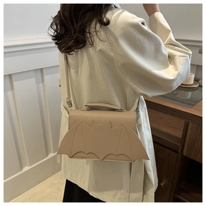 Chic beige bat wing shaped crossbody bag worn with a casual beige trench coat