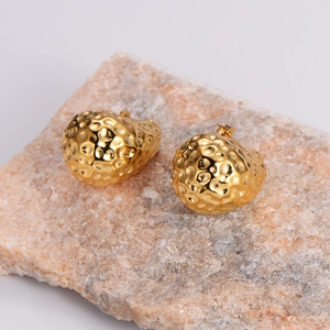Macro detail of 18K gold teardrop stud earrings with textured hammered metal finish
