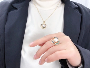 Close-up of model wearing pearl camellia pendant and ring set with rainbow abalone shell