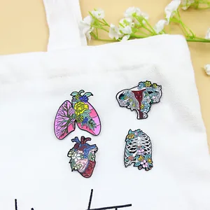 Artistic anatomical enamel pins with flowers on canvas, creative floral organ brooches