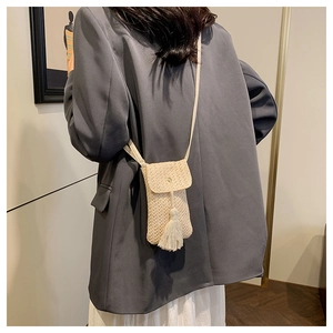 Dettaglio della borsa a tracolla intrecciata beige con nappa a frange e bottone a pressione