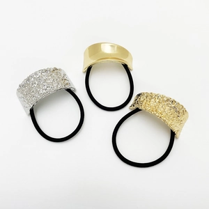 Close-up of three gold and silver punk style metallic hair ties with hammer textures
