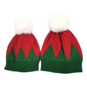 Detail view of red and green Christmas knit hats with white pom-poms for parent and child