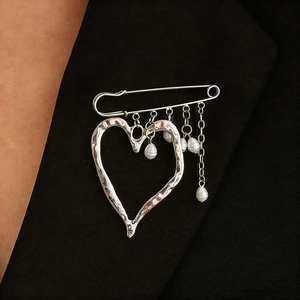 Exaggerated silver liquid lava heart brooch with pearl charms on black blazer lapel