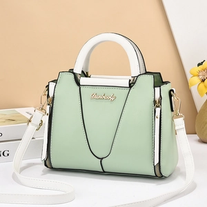 Chic green and white color-block handbag with top handles and a crossbody strap