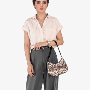 Stylish leopard print crescent underarm bag with black leather strap worn by a model