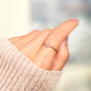 Detail view of a minimalist S925 sterling silver T-ring worn by a model in a knit sweater