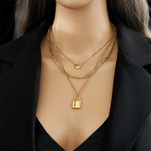 Layered gold titanium necklace featuring heart and lock pendants on a stylish model