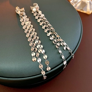 Close-up of silver sequin tassel clip-on earrings with layered metallic chain details