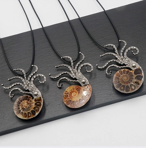 Detailed view of silver octopus pendants with natural ammonite shells on stone background