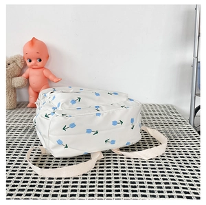 Detail of floral backpack with blue tulips on white fabric and durable beige straps