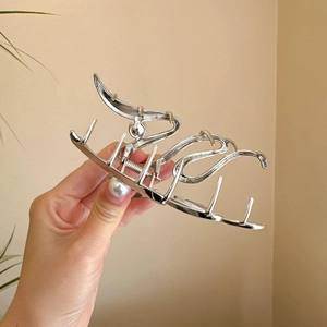 Macro view of silver fluid flame metal hair claw clip with strong spring detail