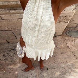 Macro shot of white hollow out crochet knit dress with halter neck and ruffled hem detail