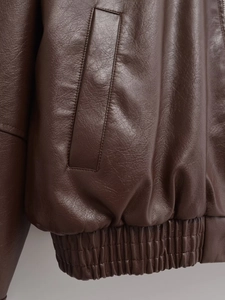 Detail of dark brown leather jacket featuring side pockets and elastic hem design