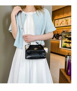 Crocodile pattern square bag with silk scarf chain shown in a stylish cafe setting