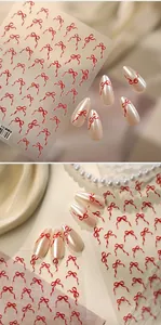 Détail de stickers à ongles nœuds rouges sur ongles nacrés avec décor élégant