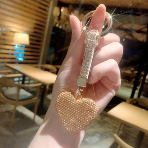 Detail of a sparkling rhinestone heart keychain with gold ring in a warm bokeh setting