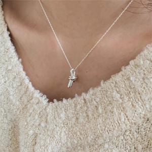 Detail view of 925 sterling silver knotted pendant necklace worn on a beige sweater