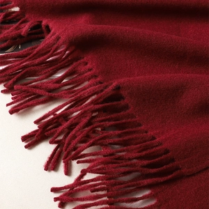 Detailed close-up of dark red cashmere-like scarf showing soft wool texture and fringe edges