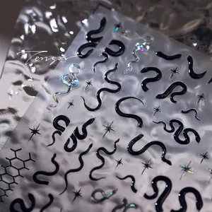 Detail of 3D embossed nail stickers featuring black snakes and laser starlight textures