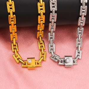 Close-up of interlocking H-link necklaces in gold and silver with zircon-set clasps