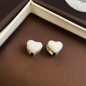 Detailed close-up of heart-shaped pearl earrings nestled in a luxury brown jewelry box
