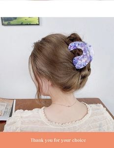 Détail d'une pince à cheveux en acétate violet avec texture marbrée sur un chignon