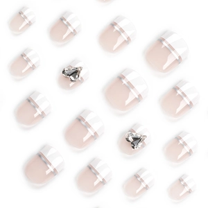 French tip press-on toenails with nude base, white edges, and glittery heart rhinestones