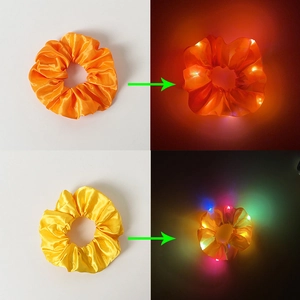Detail showing orange and yellow LED hair scrunchies glowing in dark and light settings