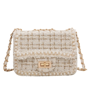 Mini cream tweed crossbody bag with pearl trim and gold chain strap in a classic style