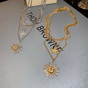 Detailed macro view of gold and silver layered necklaces with sun mask and starfish pendants