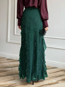 Rear view of a dark green polka dot maxi skirt with ruffle detail and flowing fabric texture
