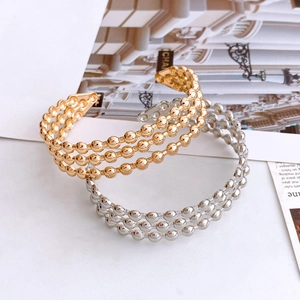 Detail of three-row gold and silver beaded open bangles with high-polished metallic finish
